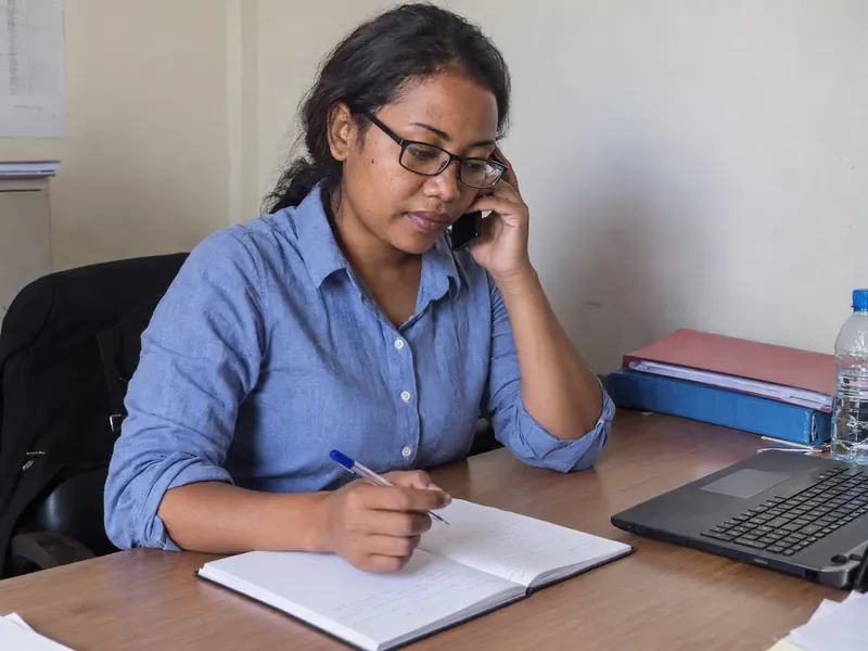 Scène illustrée : une conseillère écoute au téléphone et prend des notes.